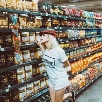 Foto de uma menina em um supermercado com vários produtos ao redor dela
