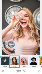 Tutorial de edição da foto de uma mulher segurando um donuts em frente ao olho e sorrindo usando a ferramenta Filtro do AirBrush