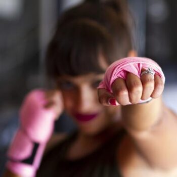 mujer boxeando con guantes rosas