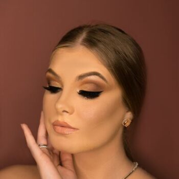 woman wearing dramatic makeup in front of a brown background