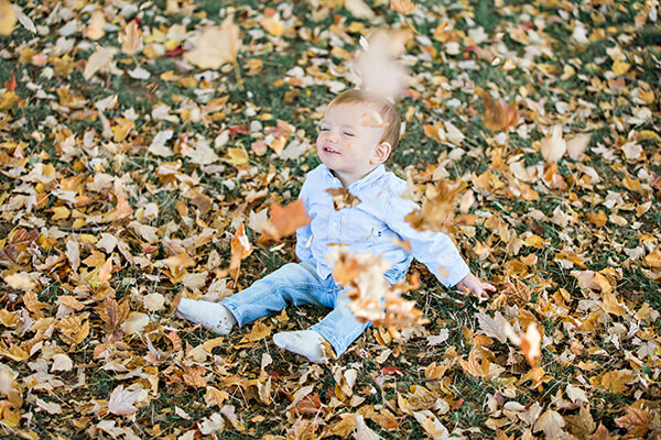 menino brincando com as folhas amarelas do outono