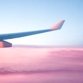 asa de avião nas nuvens rosas e céu azul
