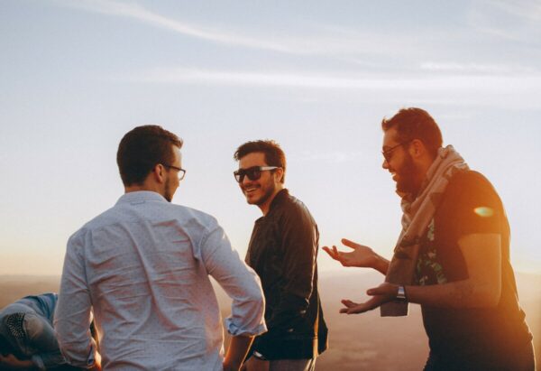 Foto de três amigos juntos e rindo durante um pôr-do-sol