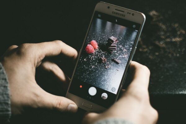 Foto da tela de um celular tirando foto de um chocolate e morangos