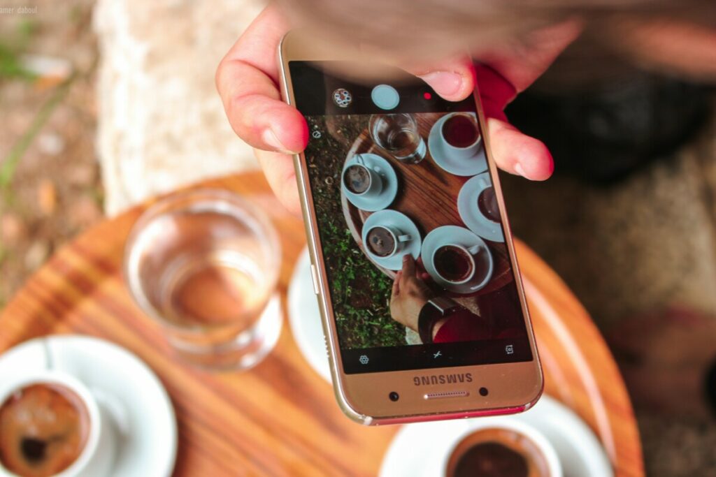 Foto da tela de um celular tirando foto de xícaras de café