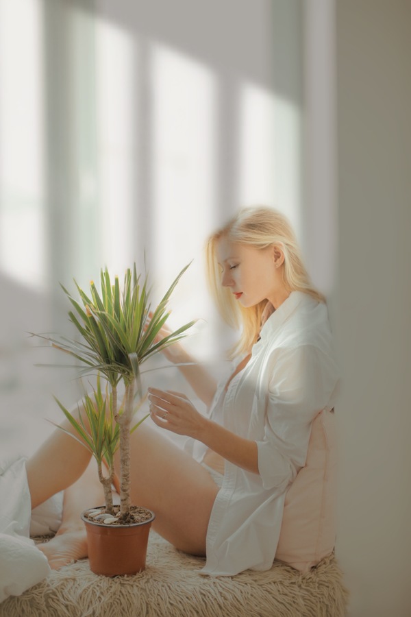 mujer sentada en su ventana con una plantita
