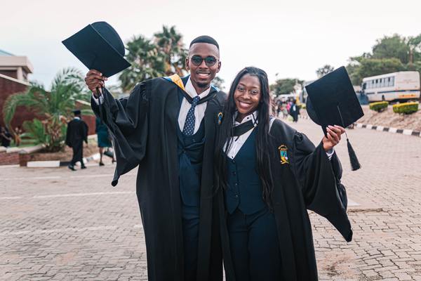 two graduates celebrating in cap and gown