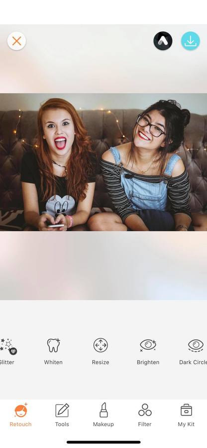 two women sitting on a gray couch, smiling