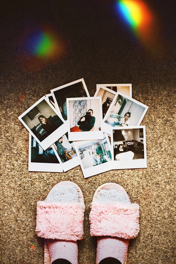 fotografías instantáneas estilo polaroid en el piso junto a unos pies 