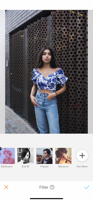 Kim Kardashian lookalike in blue jeans and floral top standing in front of metal wall