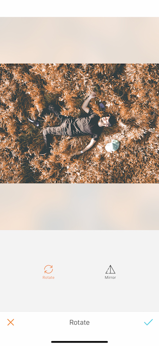 Picture of a guy lay down in a dry grass being edited by AirBrush with the Rotate Tool