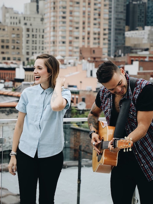 Picture of a woman and man singing and playing in a rooftop
