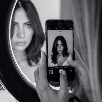 Black and white picture of a woman taking her selfie in the mirror