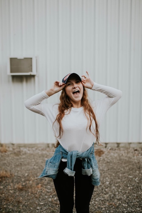 photo of woman laughing wearing a white shirt and cap