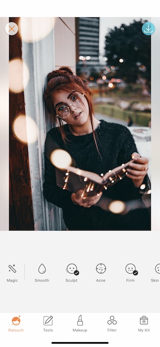 A woman with red hair with a book open being edited by AirBrush with the filter Retouch