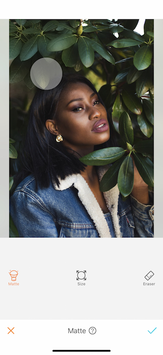 black woman in denim jacket surrounded by green leaves