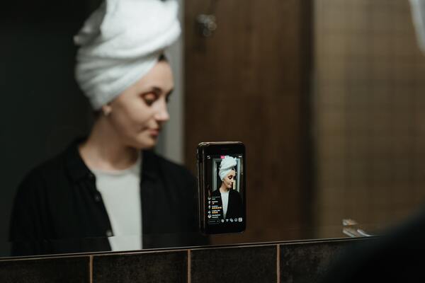 Foto de uma mulher no espelho com a toalha enrolada no cabelo 