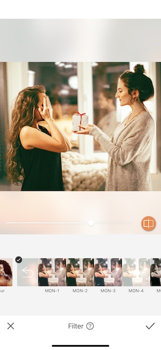 woman covers her eyes while another woman surprises her with a gift
