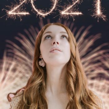 mujer rubia con cabello largo mirando hacia arriba, en el cielo está marcado "2021" como si fuera un fuego artificial