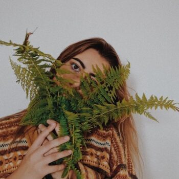 Picture of a woman with a plant in her face