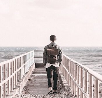 man with a backpack walking along a jetty