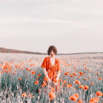 woman wearing a red dress in the middle of a field of flowers