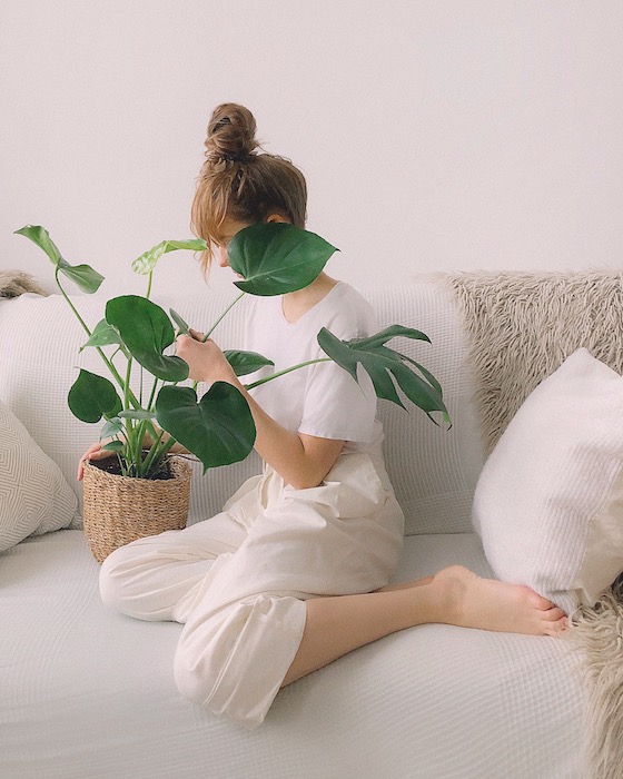 woman sitting on a white couch holding a plant