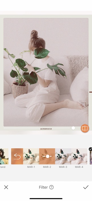 woman sitting on a white couch holding a plant