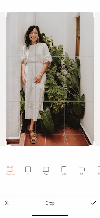  woman in a white dress standing in front of a green plant