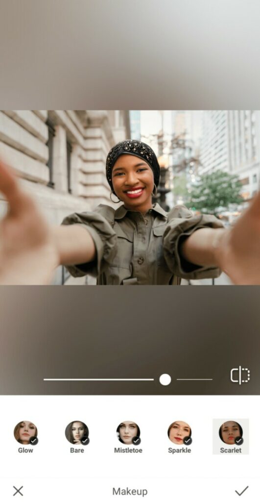 black woman wearing black head scarf taking a selfie in the city