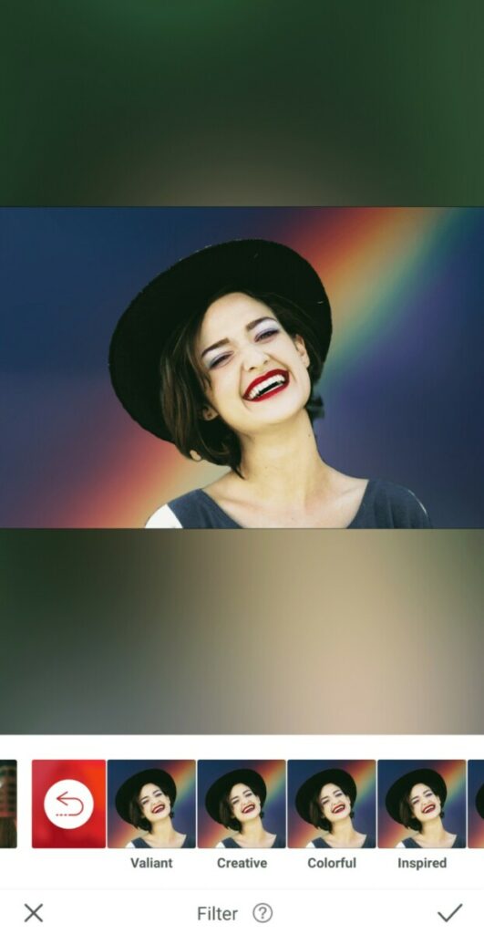 laughing woman wearing a hat in front of a rainbow background