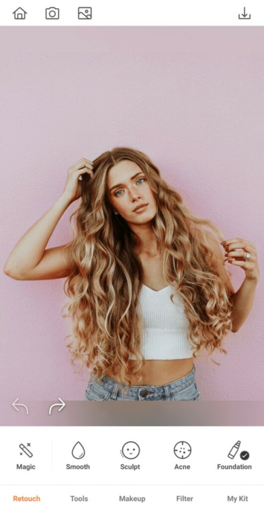 woman with curly blonde hair standing in front of a pink wall