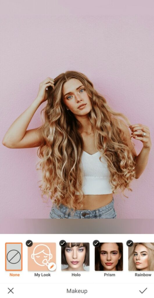woman with curly blonde hair standing in front of a pink wall