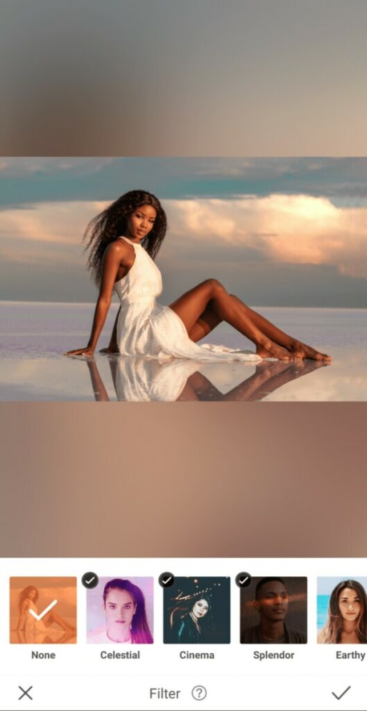 woman in a white dress sitting in water against a sunset sky