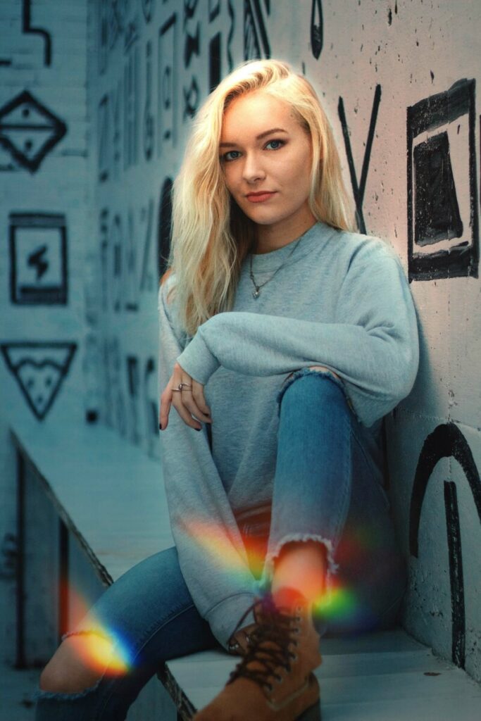 woman in grey sweater and jeans sitting in front of black and white mural