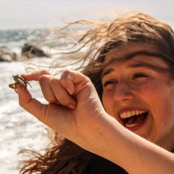 Garota sorrindo segurando um pequeno caranguejo