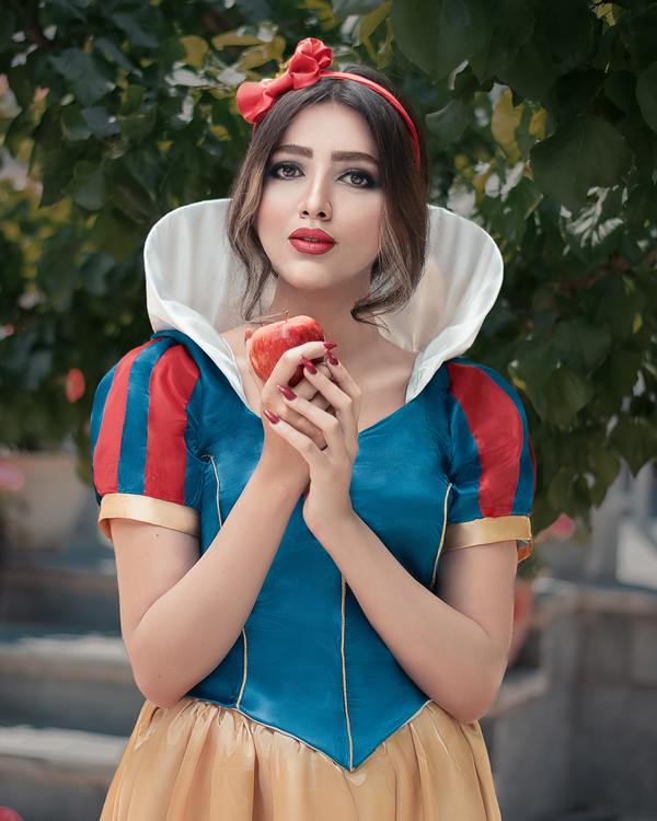 Garota vestida como Branca de Neve e segurando uma maçã