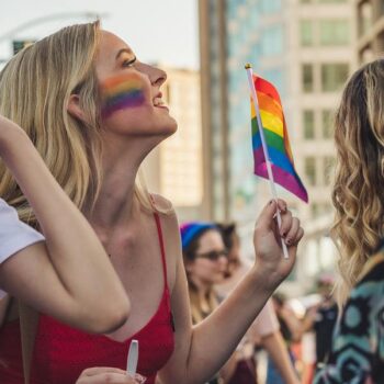 Garota segurando uma bandeira com as cores do arco-íris