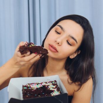 mujer comiendo una pieza de brownie con chispas de colores