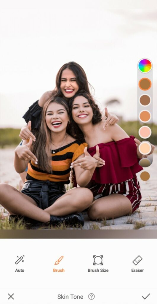 Group photo of three smiling women taking a photo on the beach