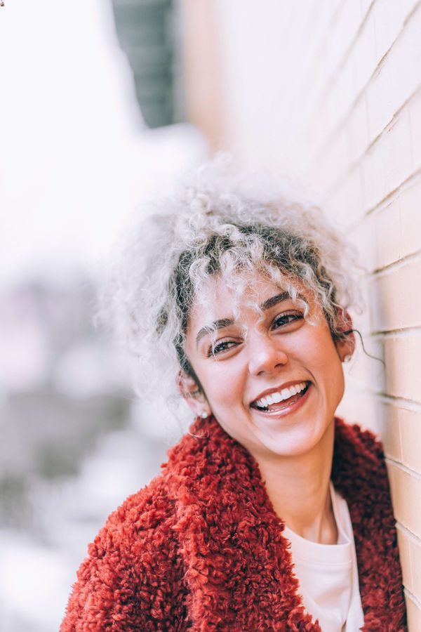 smiling woman with curly hair wearing a red jacket