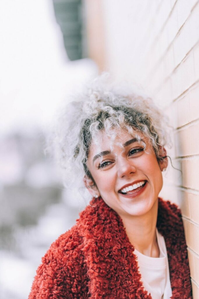 Cancer edit with smiling woman with curly hair wearing a red jacket