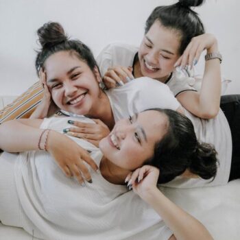 Foto de três amigas rindo e apoiadas uma a outra