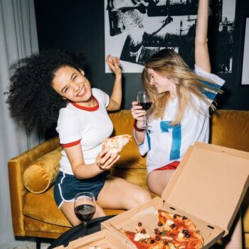 Foto de duas amigas se divertindo e comendo pizza