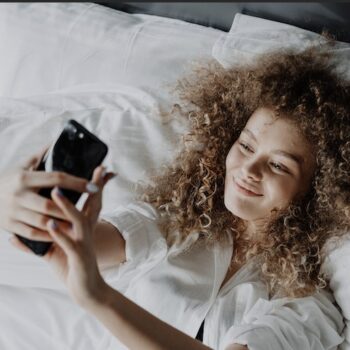 mujer viendo su celular acostada en su cama