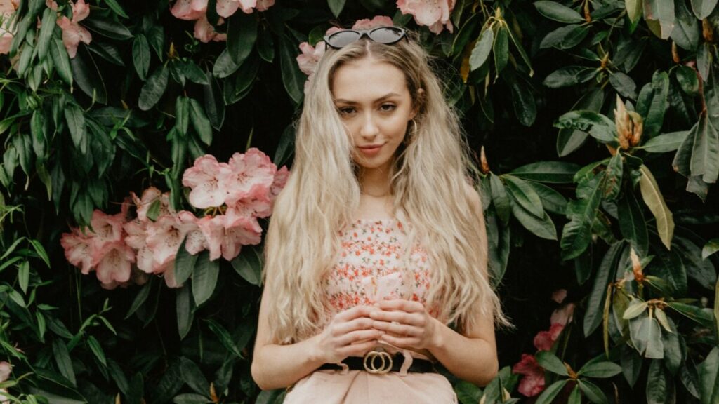 blonde woman standing in a garden