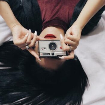 foto tirada de ponta cabeça de uma mulher segurando uma camera e tirando uma foto