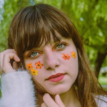 menina com franja e adesivos de flores no rosto