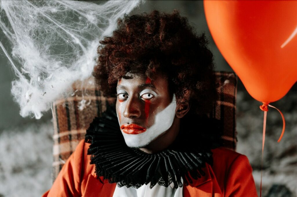 man with an afro and white pupils wearing a clown costume