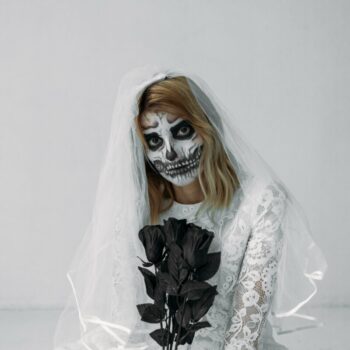 woman wearing skeleton makeup holding black flowers